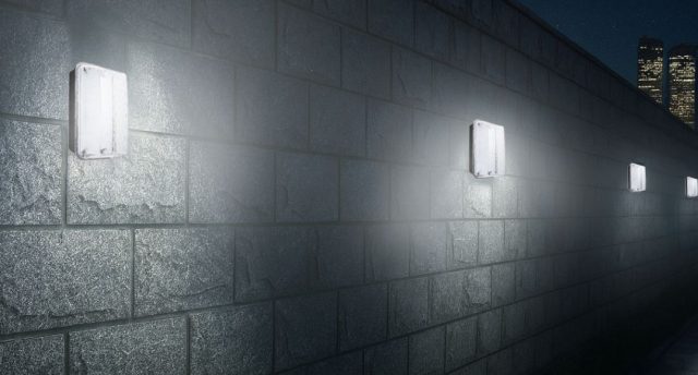 Why Commercial Spaces Are Switching to LED Bulkheads An exterior wall installed with multiple IP65 LED bulkhead lights, a skyscraper is seen in the background.