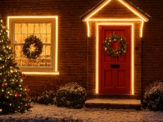 A home filled with outdoor lighting decorations and a Christmas tree in front.