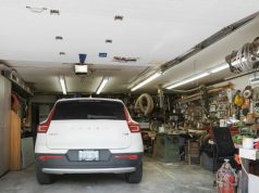 Energy-Efficient Garage Lighting: Cut Costs & Brighten Your Space A white car parked in a garage with one side of the space filled with random things.