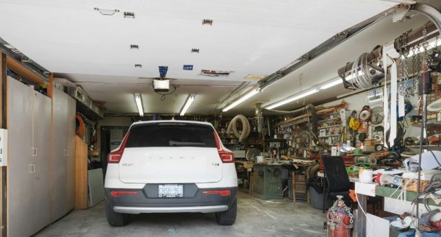 Energy-Efficient Garage Lighting: Cut Costs & Brighten Your Space A white car parked in a garage with one side of the space filled with random things.