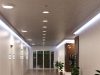 A hallway with multiple round bulkhead lights installed on the ceiling and LED strip lights glowing on both sides