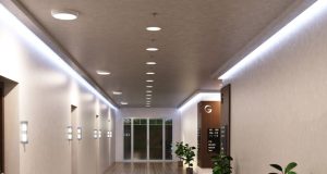 A hallway with multiple round bulkhead lights installed on the ceiling and LED strip lights glowing on both sides