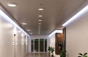 A hallway with multiple round bulkhead lights installed on the ceiling and LED strip lights glowing on both sides