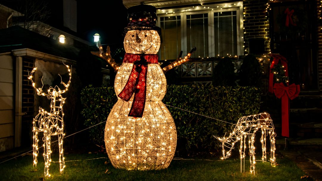 Outdoor Christmas decorations made from wire and light in the shape of a reindeer, snowman, and a sheep.