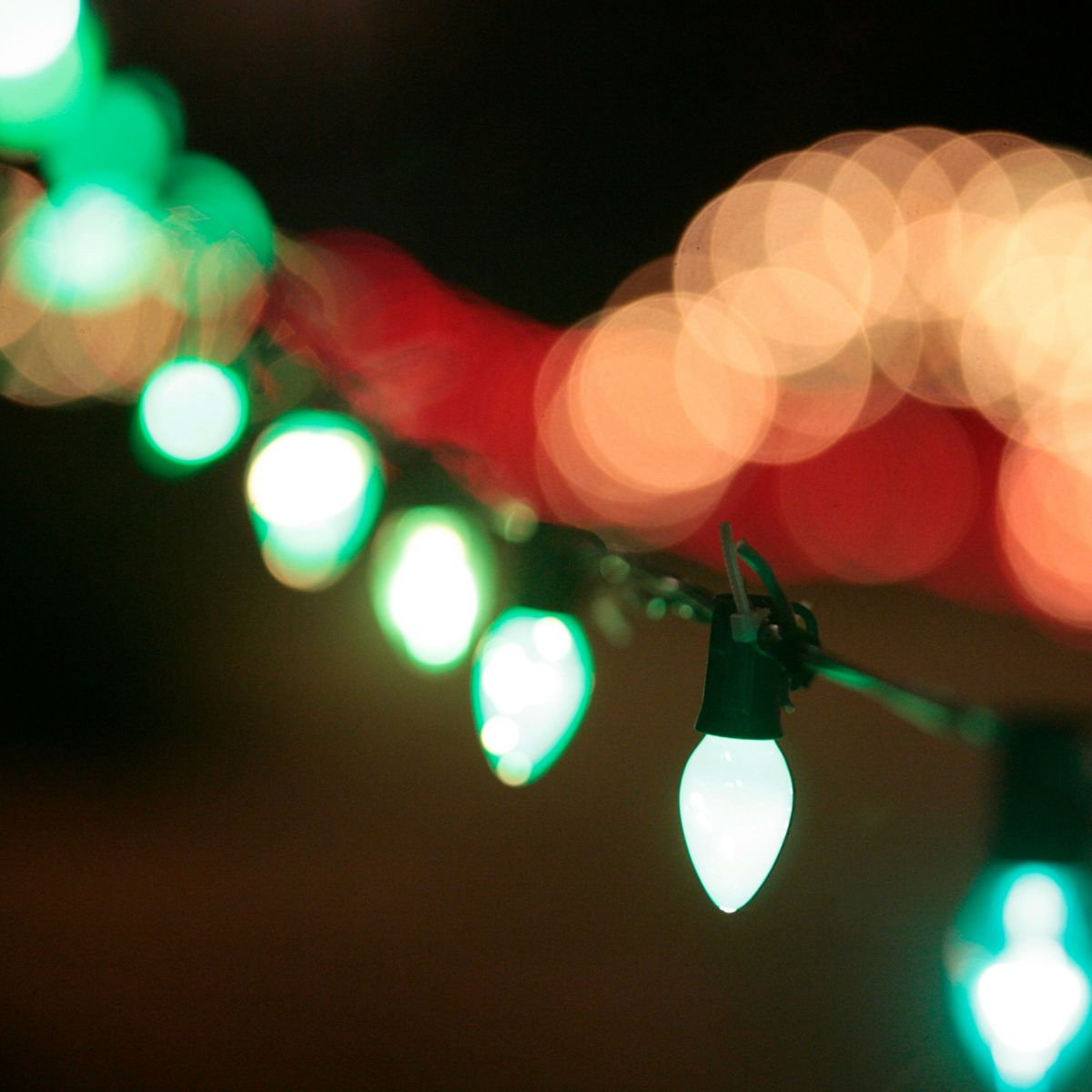 An image of a green string light with one clear bub while the rest are blurry.
