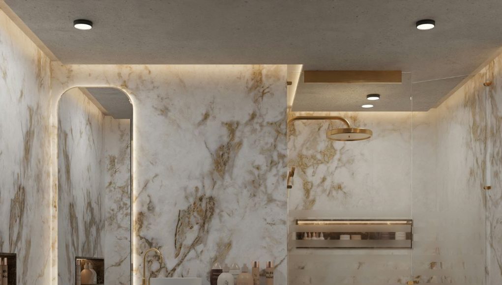 A modern bathroom with marble walls and warm ceiling and mirror lighting.