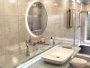 A modern bathroom with a round LED mirror over a vanity, and the shower area is behind a glass partition.