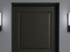 A dark grey door with two bulkhead lights installed on both sides, glowing with natural white light.