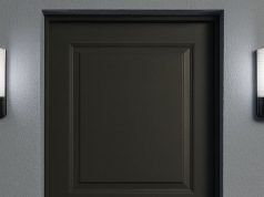 A dark grey door with two bulkhead lights installed on both sides, glowing with natural white light.