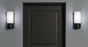 A dark grey door with two bulkhead lights installed on both sides, glowing with natural white light.