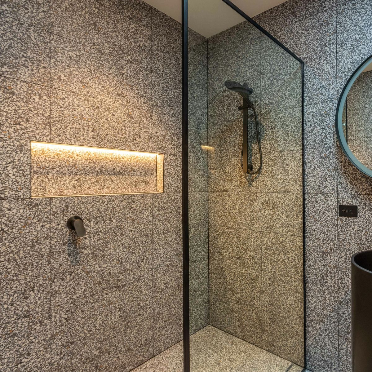 A shower area with an illuminated niche.