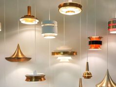 Multiple hanging lights illuminating a white wall.