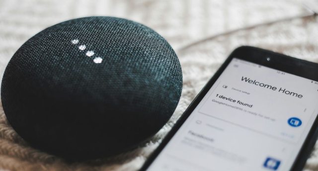 Voice-Controlled Lighting: How Alexa and Google Home Make Life Easier A smartphone beside a Google Home Mini speaker.