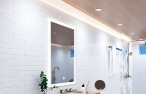 A bright modern bathroom with an LED bathroom mirror, strip lights lining the ceiling, and multiple LED downlights.