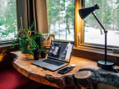 Home Office Lighting Ideas to Boost Productivity A wooden desk stationed by the window with a desk lamp glowing with warm light beside it.