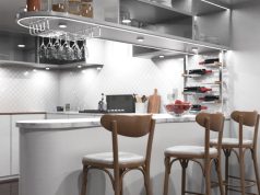 A modern kitchen with an island/bar area and bar stools, under-cabinet lights are illuminating the space.