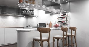 A modern kitchen with an island/bar area and bar stools, under-cabinet lights are illuminating the space.