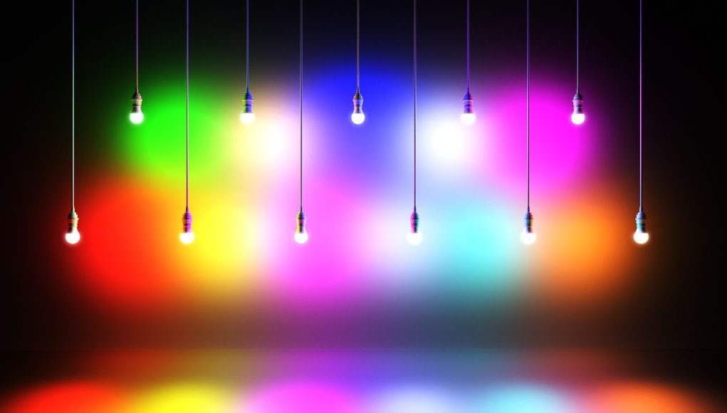 Two rows of lights with different colours hanging in two different heights in a dark room.