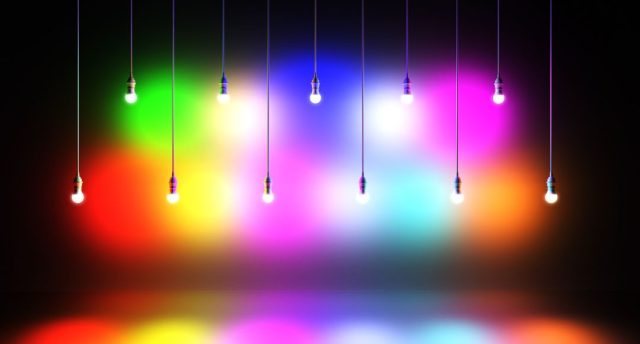 Two rows of lights with different colours hanging in two different heights in a dark room.
