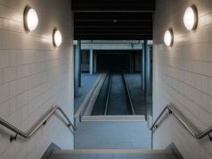 A stairwell going down with multiple round bulkhead lights on both sides.