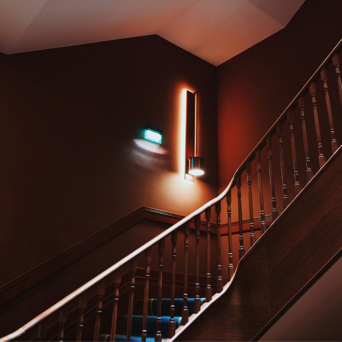 A staircase with multiple lights installed on the wall to illuminate the bend.