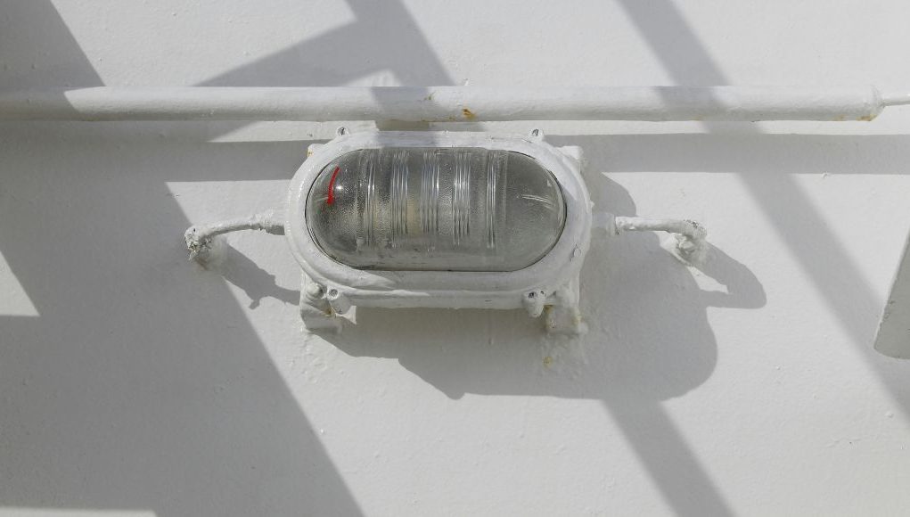 ATEX Zone Lighting hero image A bullhead installed on a wall just below a pipe, painted white as the wall.