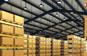 High Bay LED Lighting: How to Choose the Right Solution for Your Warehouse A warehouse with multiple boxes on racks and multiple high bay lights hanging from the ceiling.
