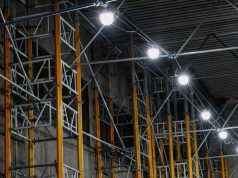 Industrial LED Lifespan & Maintenance: Reducing Downtime Costs A series of big, bright lights installed along steel beams inside a warehouse.
