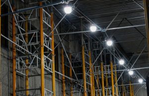Industrial LED Lifespan & Maintenance: Reducing Downtime Costs A series of big, bright lights installed along steel beams inside a warehouse.