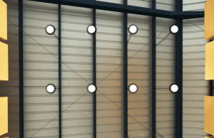 A ware house ceiling lined with multiple high bay lights with white glow, boxes on racks to the side.