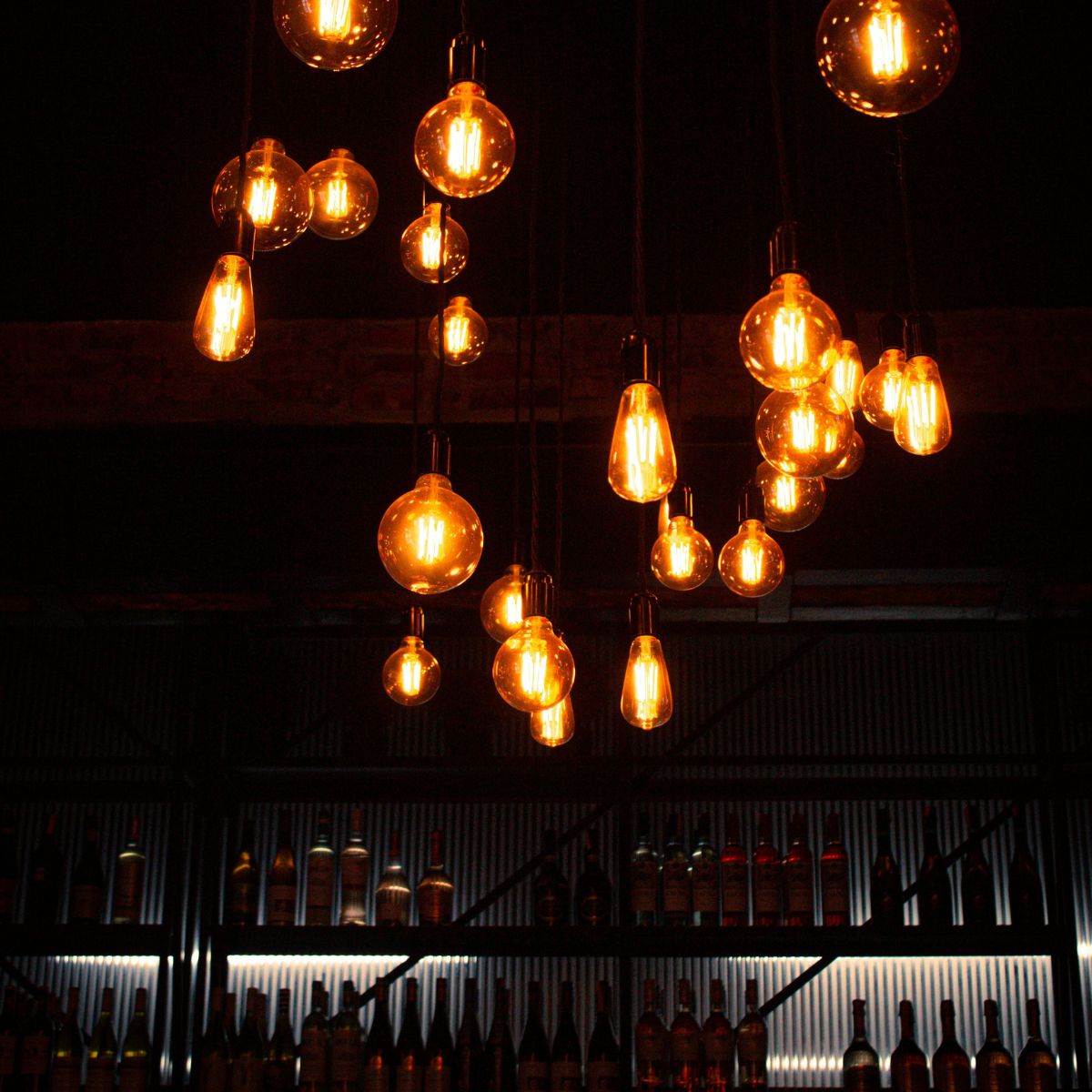 Multiple warm LED filament light bulbs hanging from a dark ceiling.