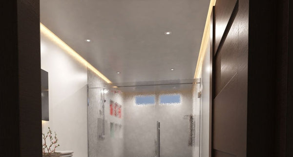A view from the door of a modern bathroom showcasing its warm LED strip lighting along the ceiling.