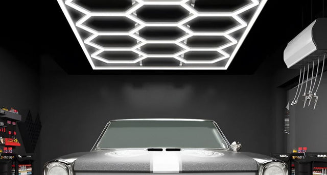 A modern garage with black walls and ceiling, a project car at the centre, and above it is a honeycomb LED light setup.