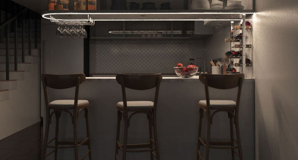 Dim kitchen island with bar stools illuminated by strip light from the shelf above.