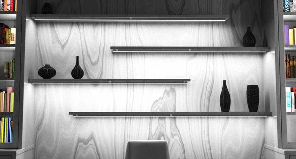 An office wall lined with shelves with LED strip lighting under each level.