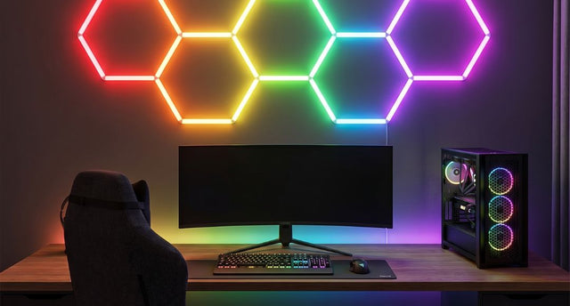 A PC gaming setup with an RGB hexagon light on the wall as a feature.