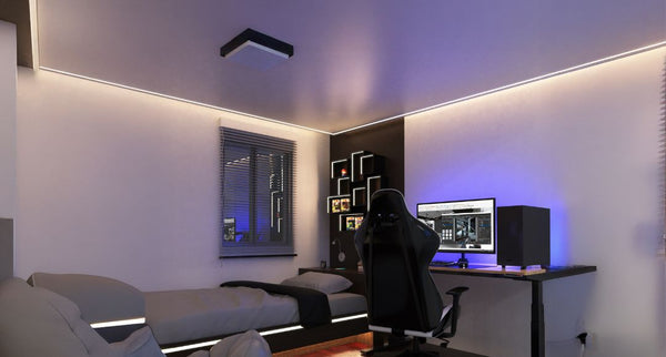 A small bedroom with a PC setup and LED strip ceiling lighting.