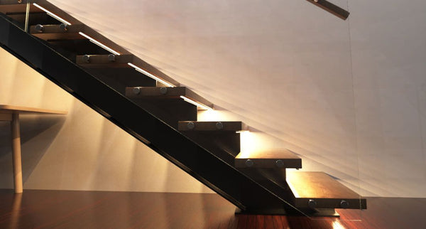 The side of a staircase with warm lights under every step.