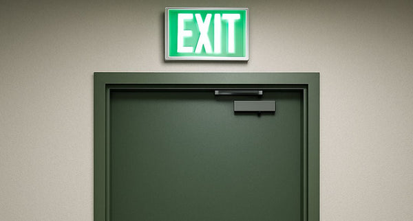 A lit EXIT sign over a green door.