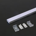 A close-up on one end of an aluminium profile with a white diffuser laid on a dark surface beside mounting accessories: two mounting brackets and two end caps.