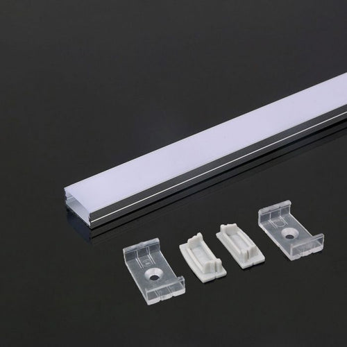 A close-up on one end of an aluminium profile with a white diffuser laid on a dark surface beside mounting accessories: two mounting brackets and two end caps.