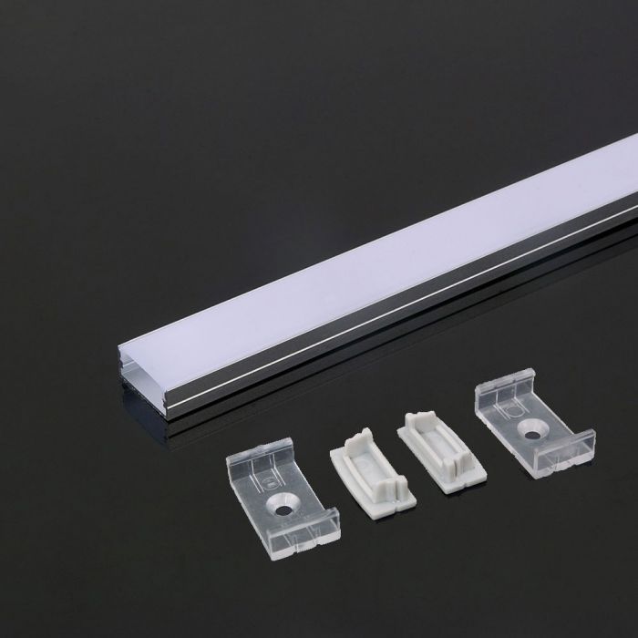 A close-up on one end of an aluminium profile with a white diffuser laid on a dark surface beside mounting accessories: two mounting brackets and two end caps.