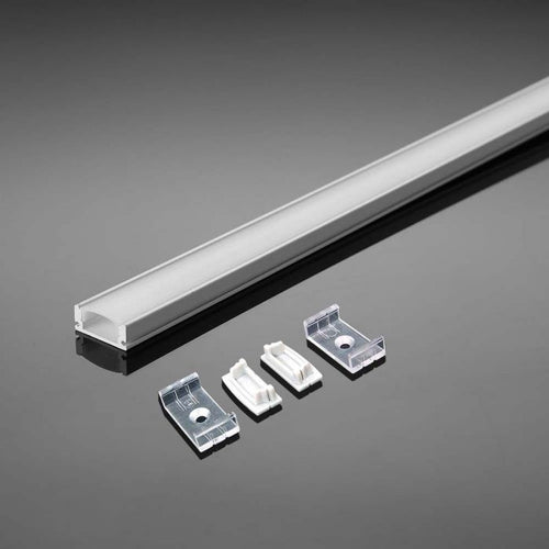 An aluminium profile with a white diffuser laid on a reflective grey surface, along with two mounting brackets and clips.