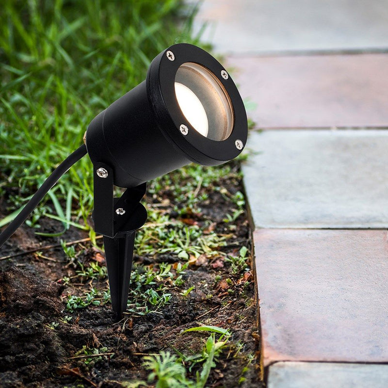 Full shot of a black LED garden light on the ground with warm white light