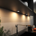 mid-shot of a kitchen with mounted black LED CCT cabinet lights - warm white light