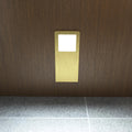 Front view of the slim under cabinet light with a brushed brass finish, installed under a wooden surface, and glowing with a cool white tone.