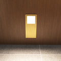 Front view of the slim under cabinet light with a brushed brass finish, installed under a wooden surface, and glowing with a natural white tone.