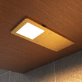 Warm white glow on the ultra-slim brushed brass under cabinet light mounted under a wooden surface.