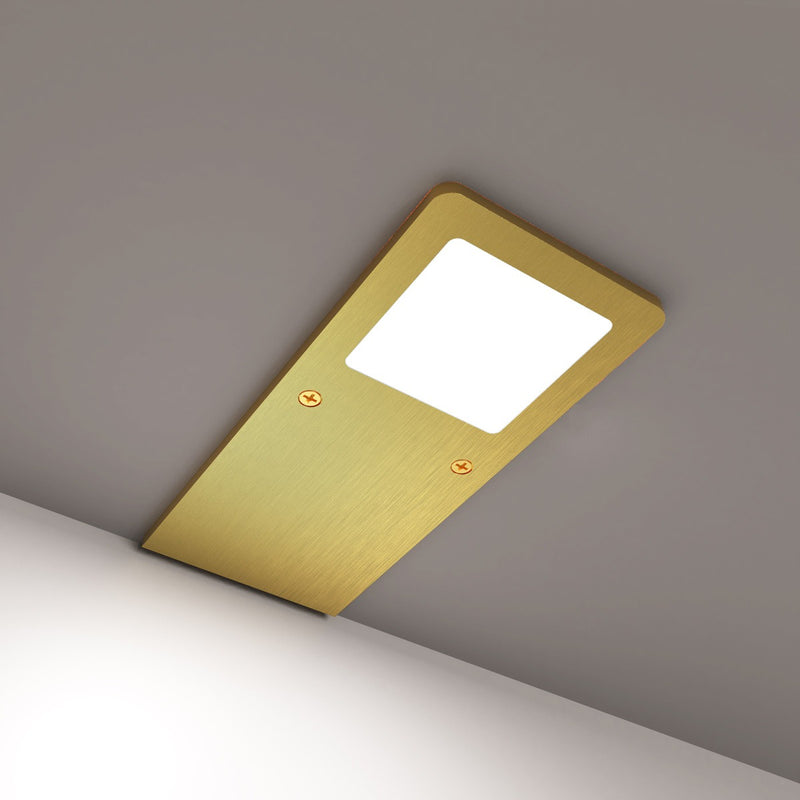 Brushed brass ultra-slim under cabinet light with a natural white glow, screwed to a grey surface.