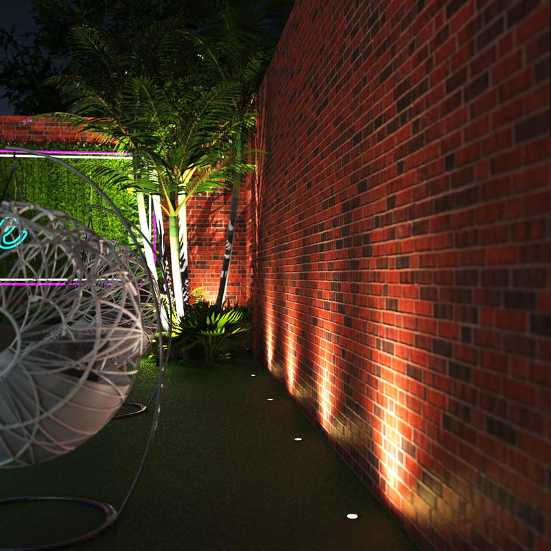 Full shot of a garden with ground lights lined across a brick wall